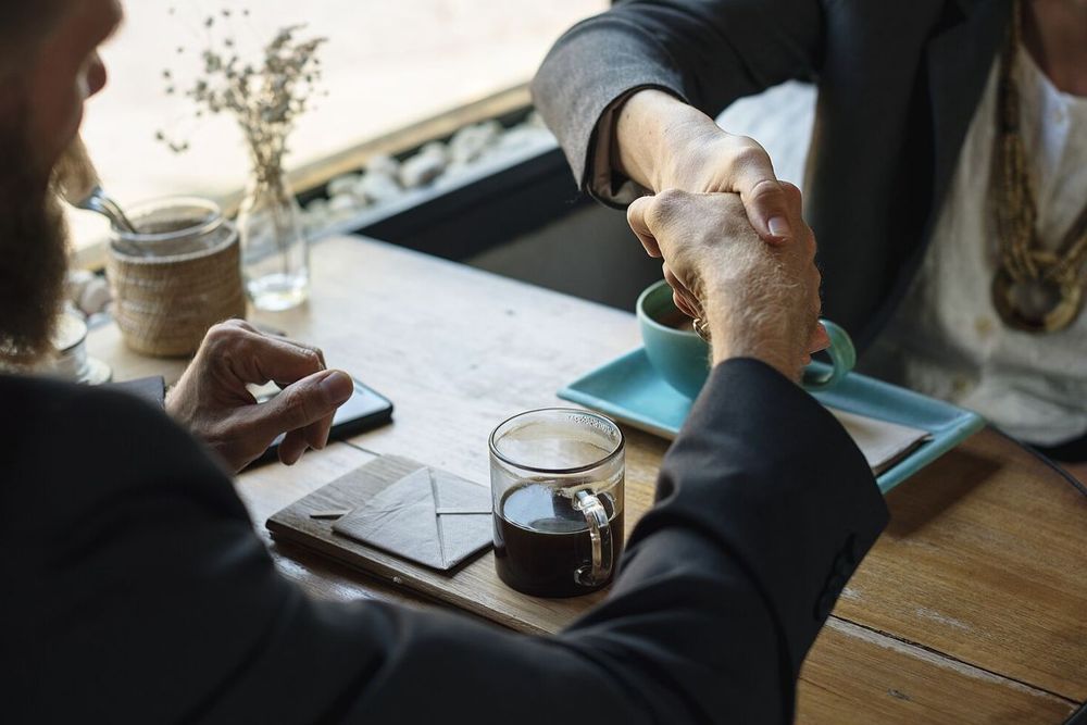 Two people shaking hands across a table