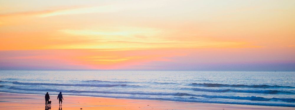 A family walking on a beach at sunset